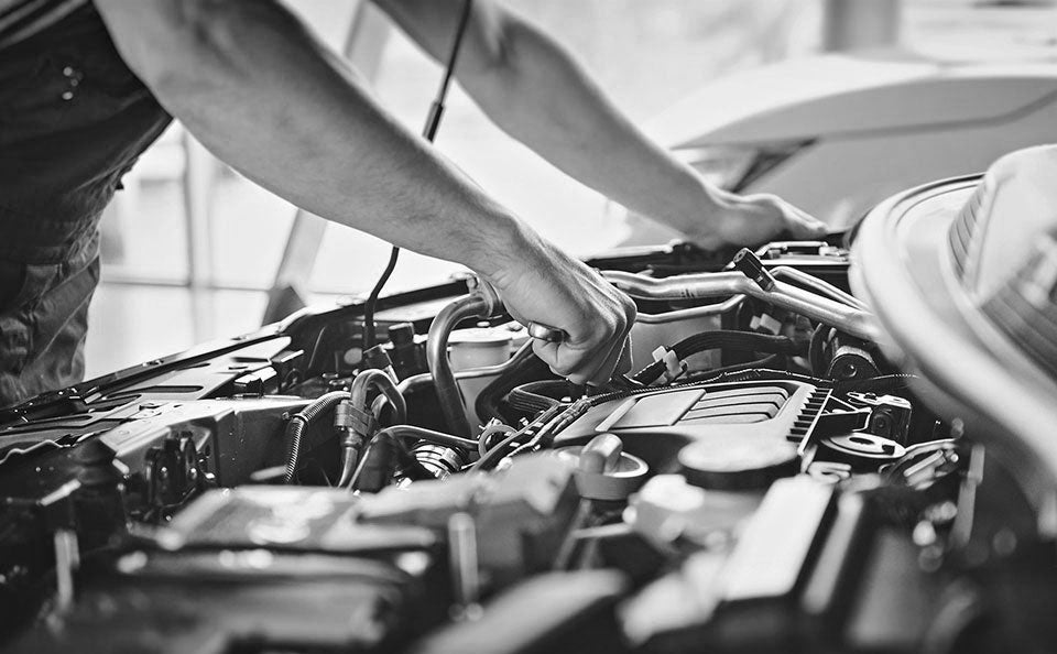 image of the arms and hands of a mechanic working under the hood of a vehicle